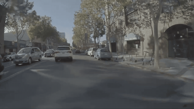 The view from a front-facing vehicle camera showing a real world drive down a busy street reconstructed in simulation.
